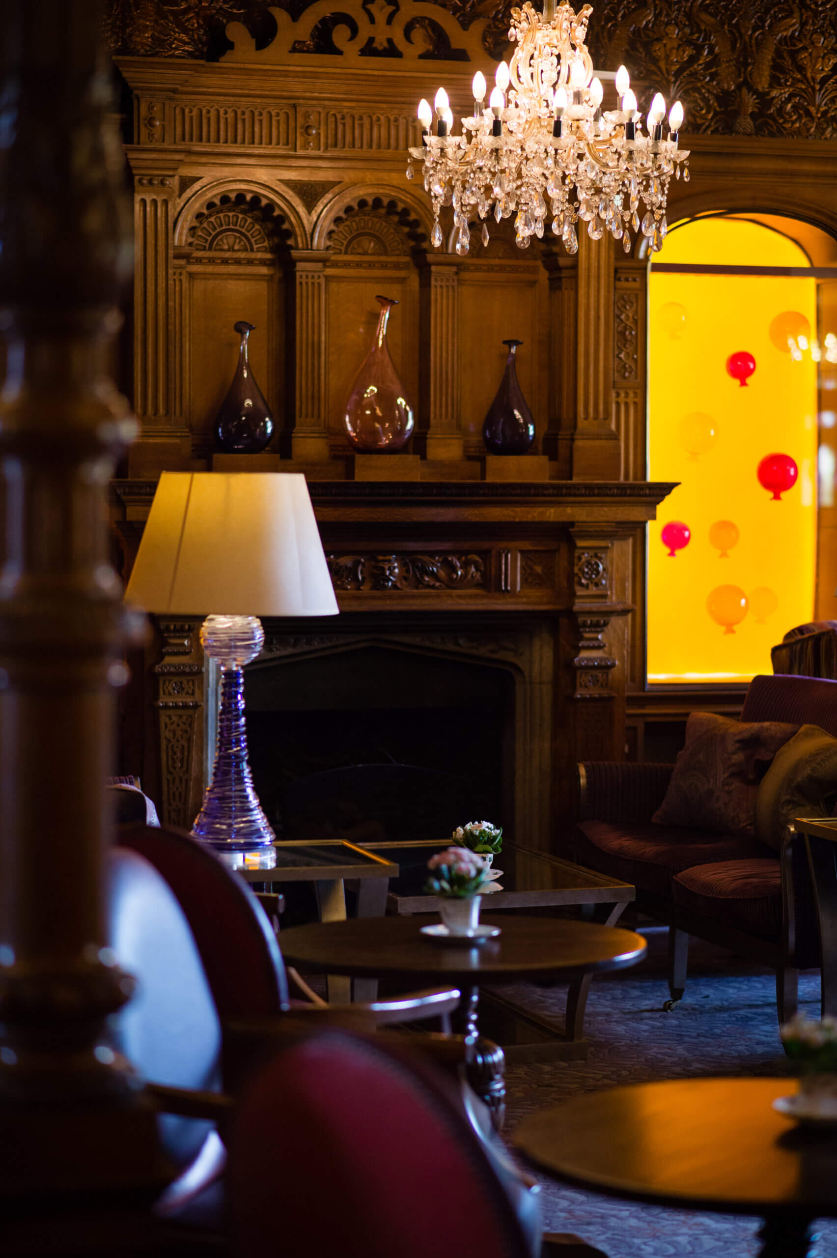 A warmly lit room with fancy wooden panelling and an ornate fireplace.